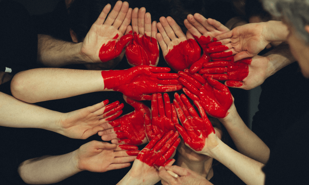 Red Heart painted on a group of people's hands
