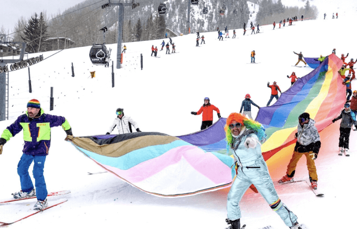 Group of people skiing holding big pride flag